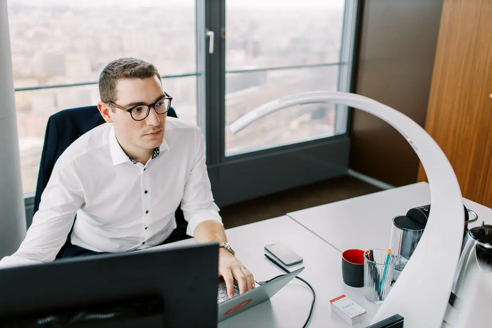 Homme d'affaires concentré travaillant sur son ordinateur portable dans un bureau avec vue.