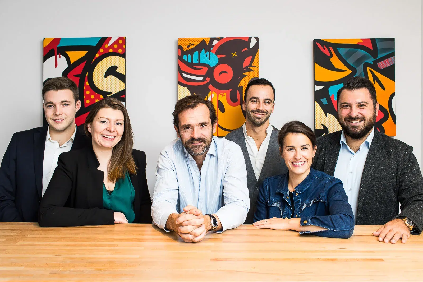 Portrait d'équipe dynamique devant des œuvres pop art par un photographe corporate Lyon.