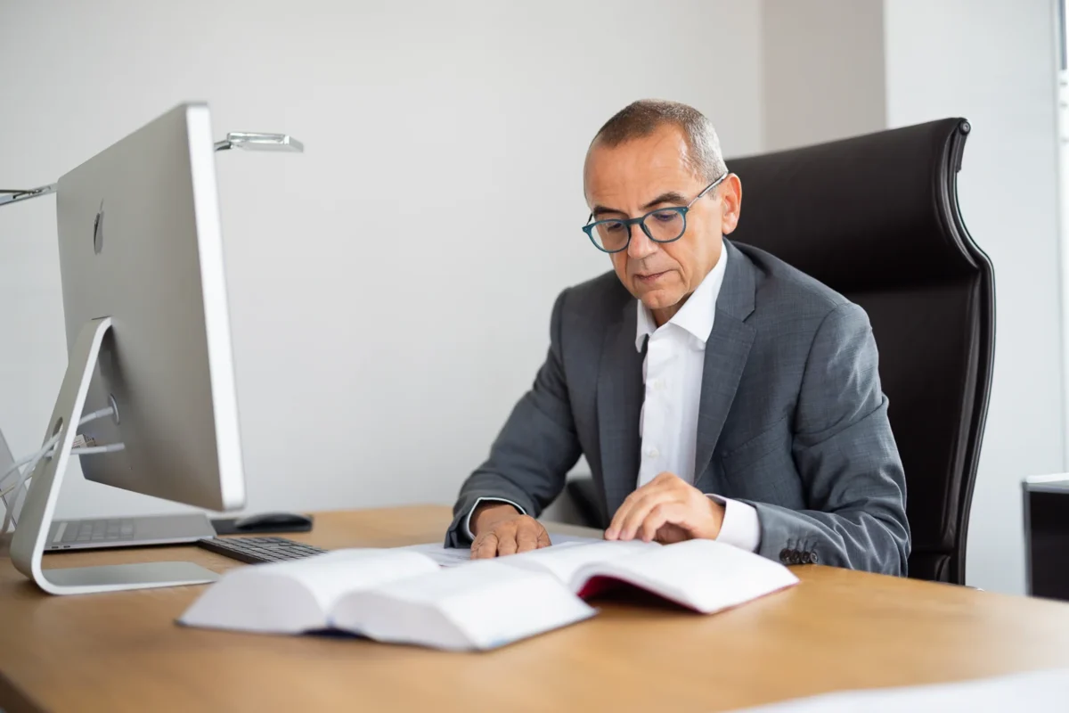 Photographe corporate Lyon capturant un avocat ou dirigeant concentré sur un ouvrage juridique à son bureau.
