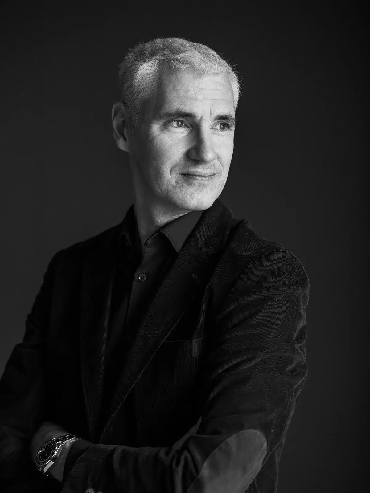 Portrait en noir et blanc d'un homme en veste sombre regardant vers la droite.