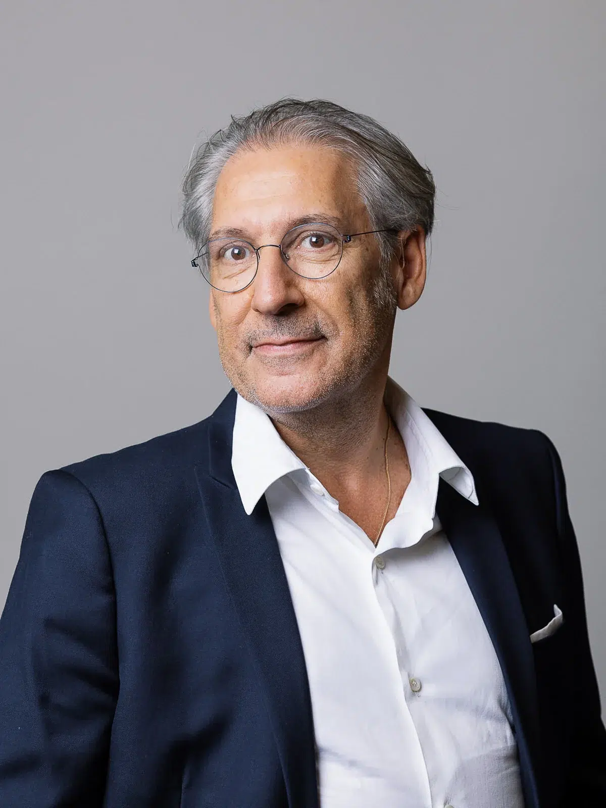 Portrait corporate d'un homme aux cheveux gris portant des lunettes rondes et une veste sombre photographié par un photographe corporate Lyon.