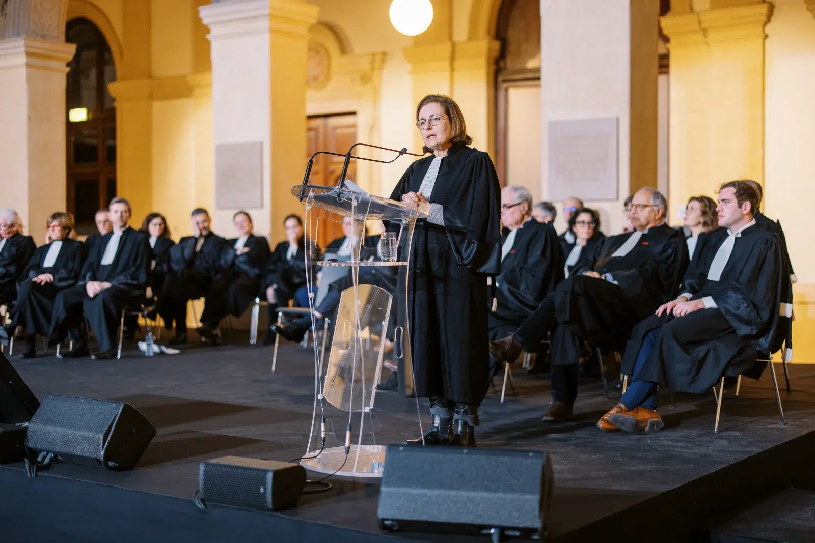 Oratrice en robe d'avocat saisie par un Photographe event Lyon lors d'une cérémonie solennelle sous les voûtes.