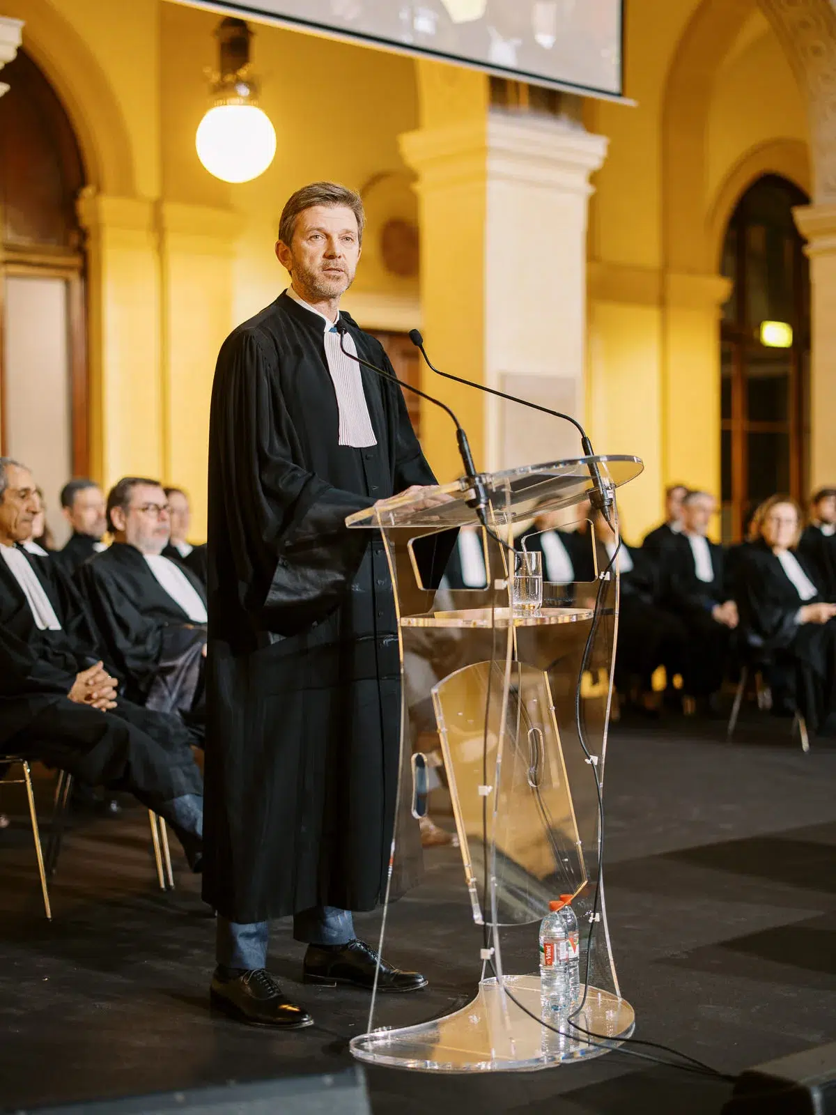 Photos événement Lyon : un magistrat en robe prononce un discours solennel au pupitre lors d'une cérémonie officielle.