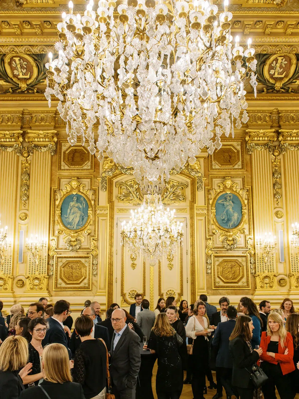 Photographe event Lyon : vue d'ensemble d'une réception élégante dans un salon majestueux orné de dorures et de lustres en cristal.