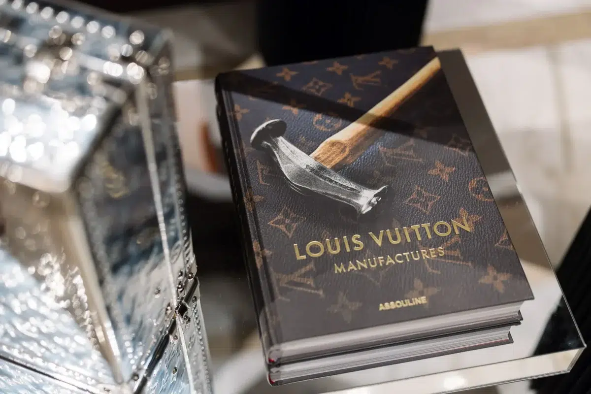 Photographe événementiel Lyon : gros plan sur un livre 'Louis Vuitton Manufactures' posé sur une table en verre.