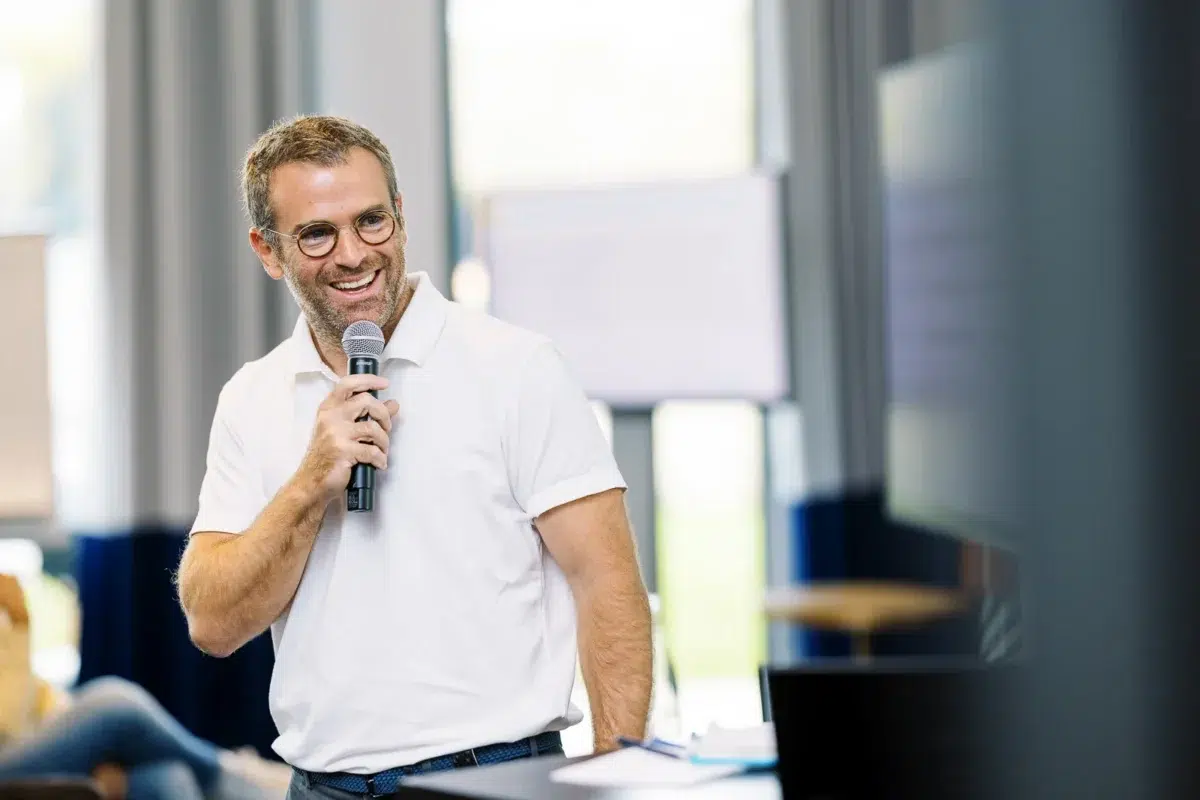 Photographe event Lyon : portrait d'un homme souriant au micro lors d'une présentation professionnelle.