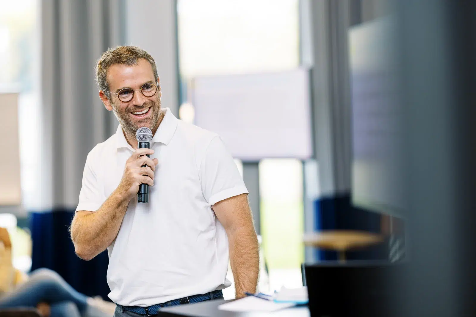 Photographe event Lyon : portrait d'un homme souriant au micro lors d'une présentation professionnelle.