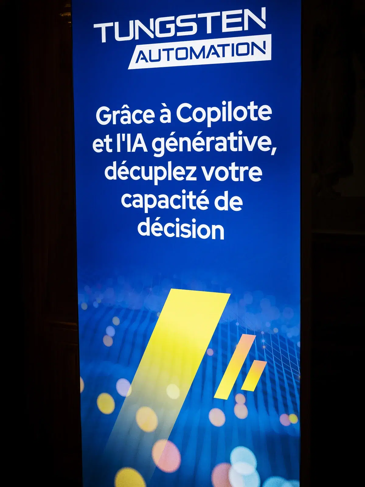 Photographe événementiel Lyon : panneau d'affichage bleu avec le logo Tungsten Automation et un texte sur l'IA générative.