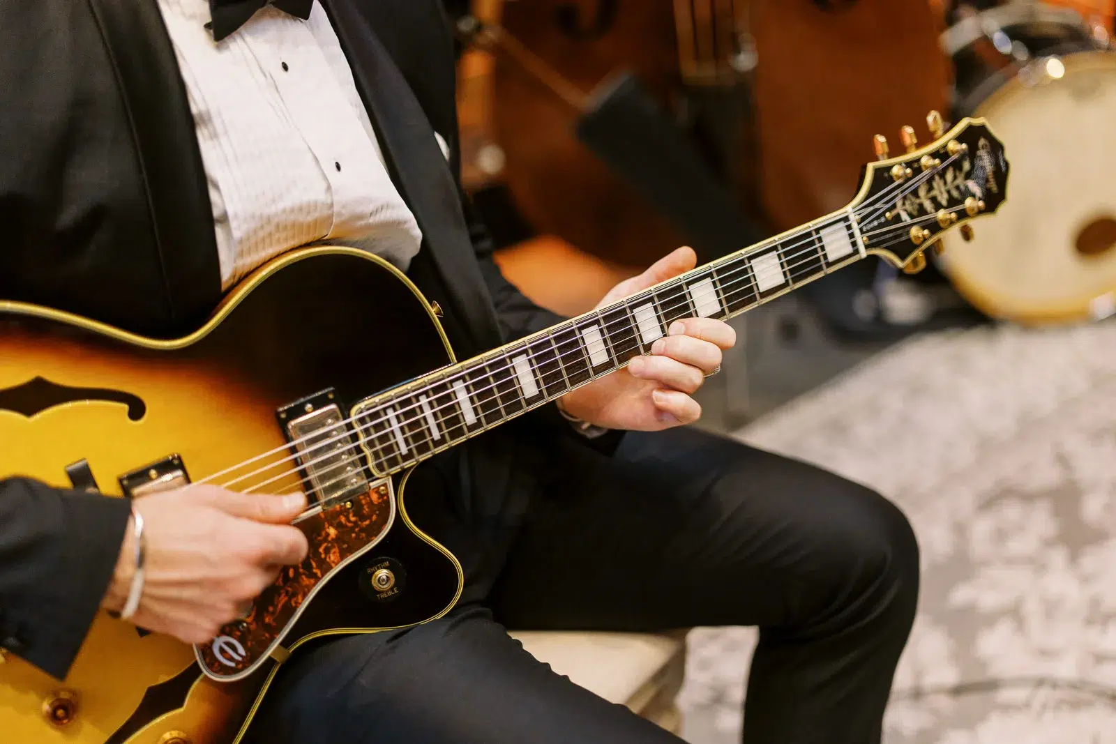 Photographe event Lyon : gros plan sur les mains d'un guitariste en costume jouant d'une guitare électrique lors d'un événement.