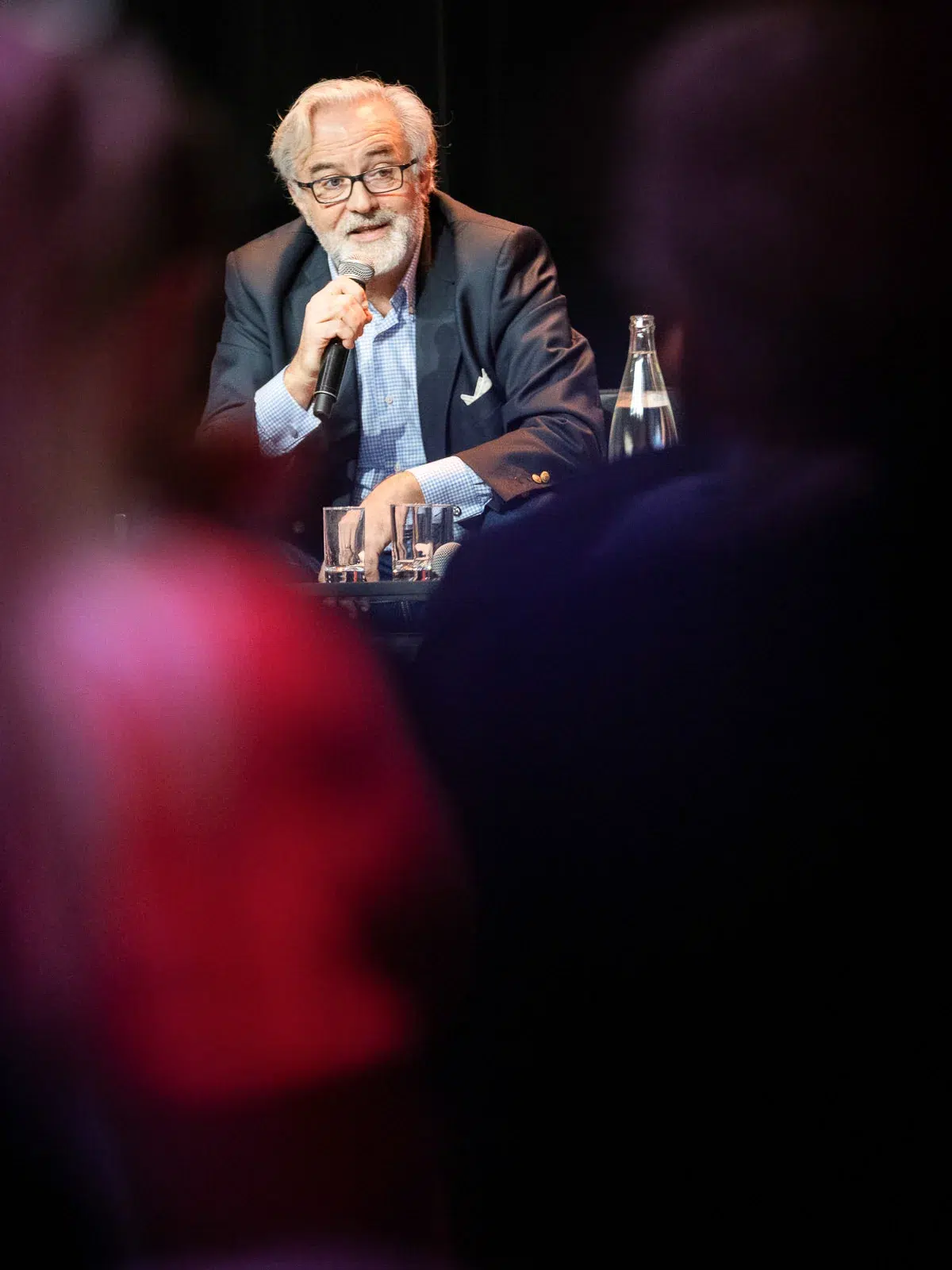 Photographe event Lyon : un homme aux cheveux blancs répond à des questions au micro lors d'une interview sur scène.