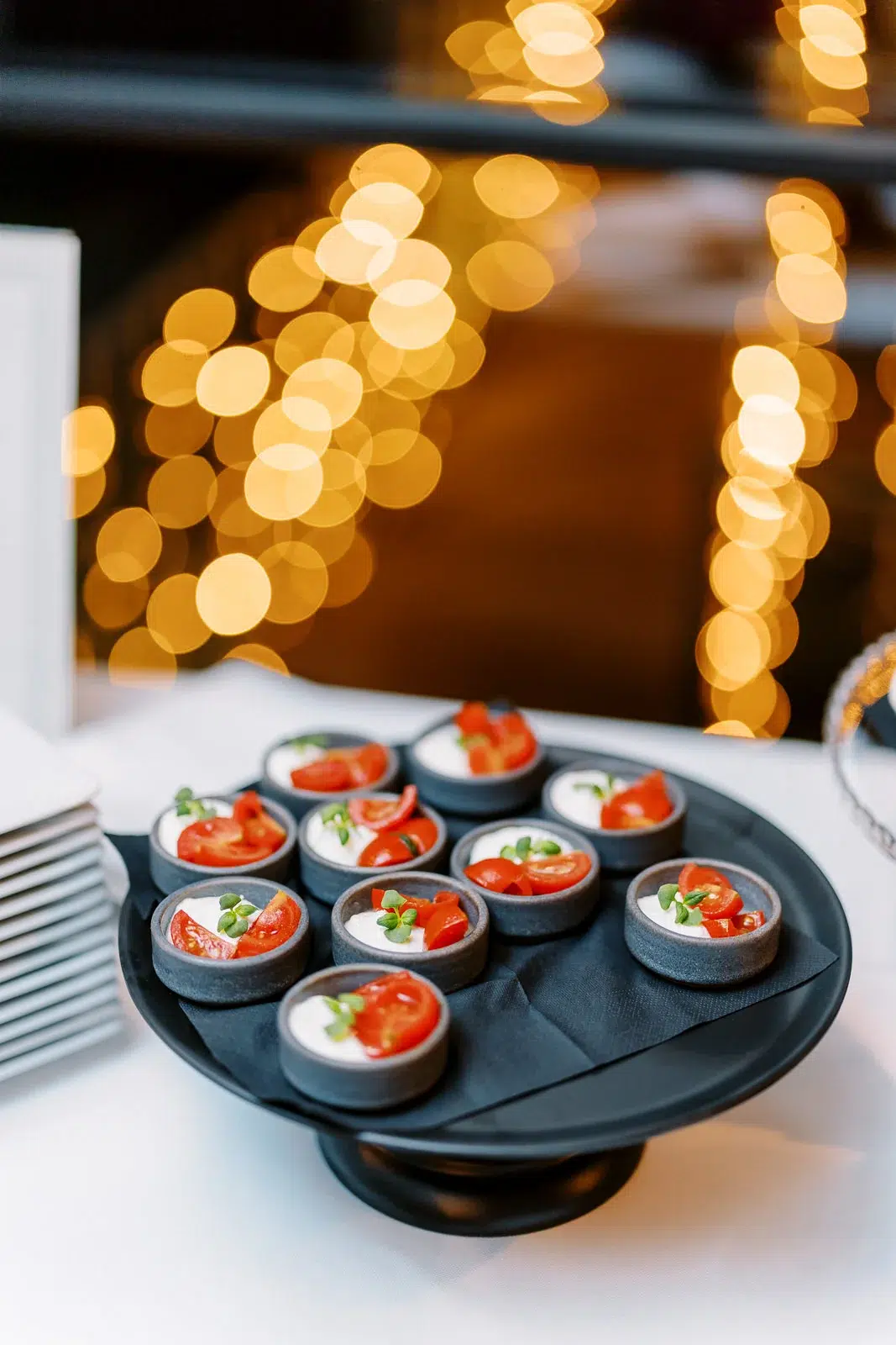 Photographe événementiel Lyon immortalisant des amuse-bouches tomates mozzarella sur un plateau avec un bokeh doré en fond.