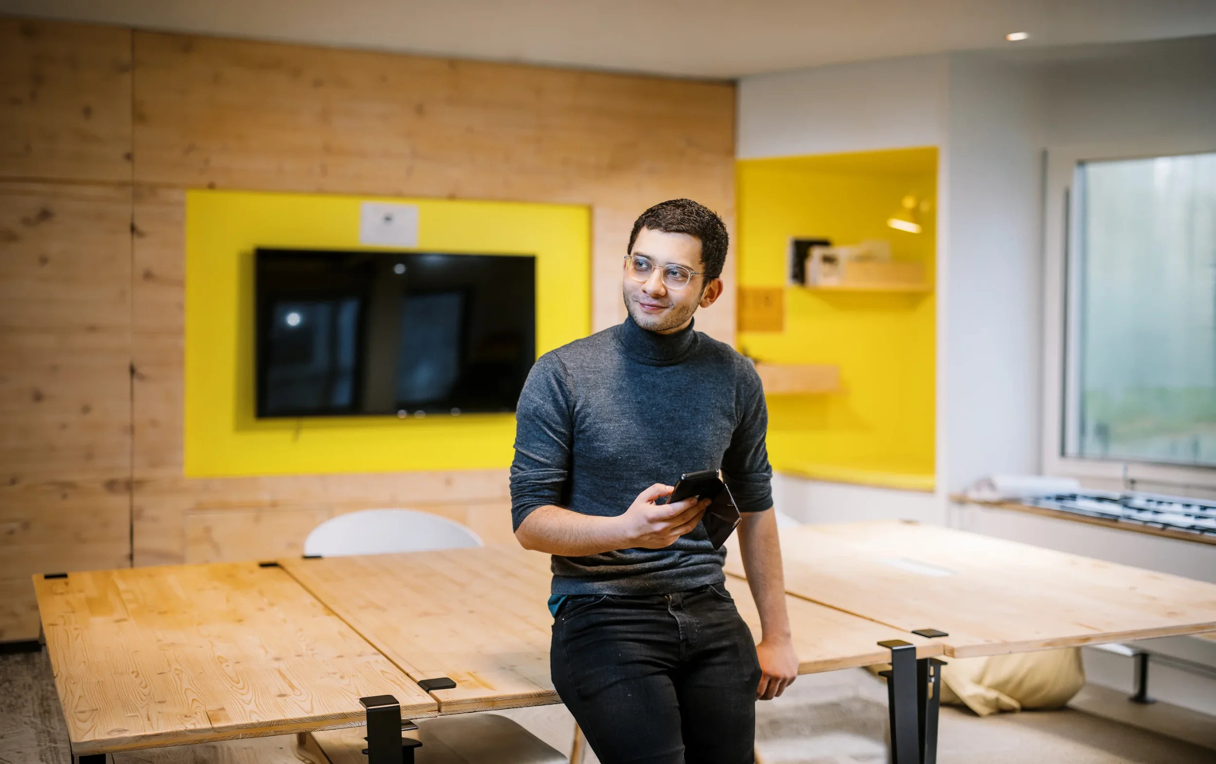 Jeune professionnel avec smartphone dans un bureau design, par un photographe pro Lyon.
