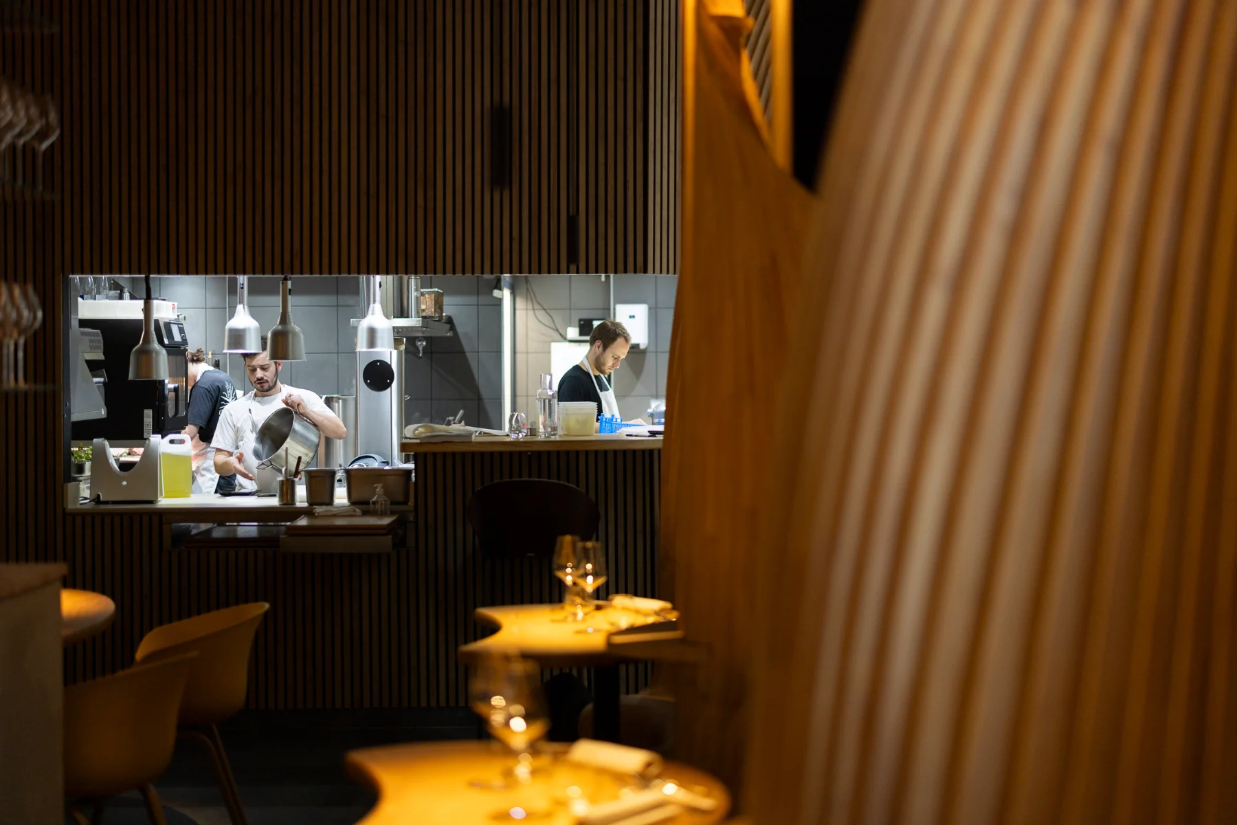 Reportage d'un photographe de reportage à Lyon capturant des chefs en cuisine ouverte dans un restaurant moderne.