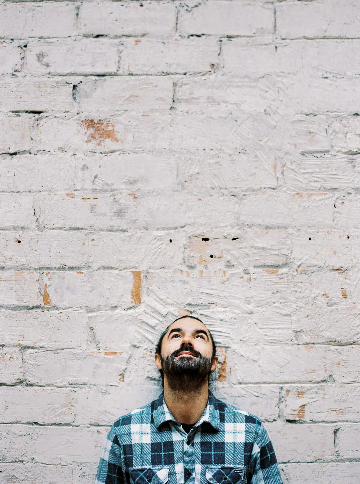 Photographe portrait Lyon : homme barbu en chemise à carreaux regardant vers le haut.