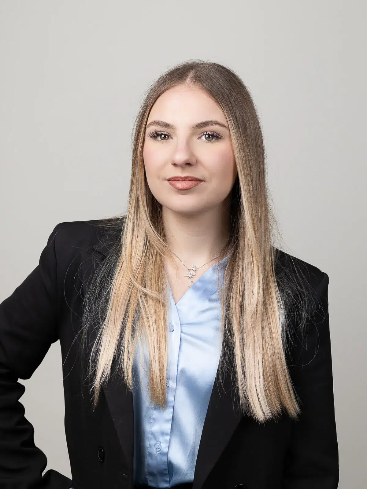 Photographe portrait Lyon : jeune femme blonde en blazer noir et chemisier bleu satiné.
