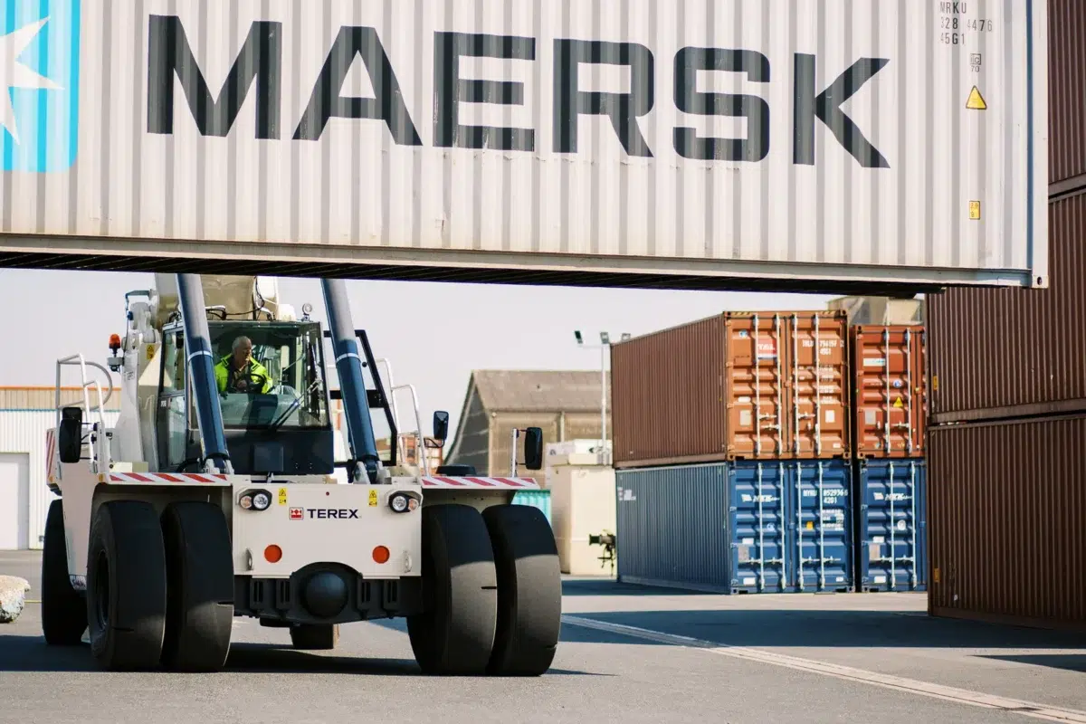 Reportage photo Lyon : Un reach stacker soulève un conteneur Maersk sur un terminal portuaire.