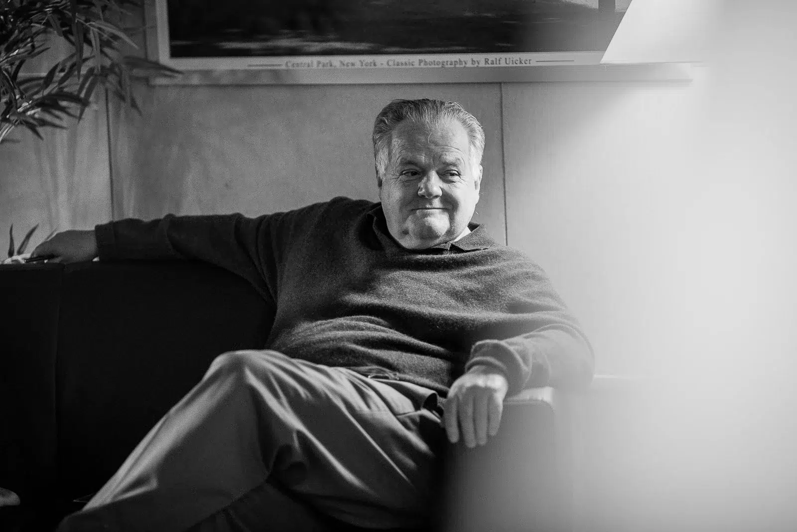 Photographe portrait Lyon : homme âgé assis sur un canapé dans un salon chaleureux.