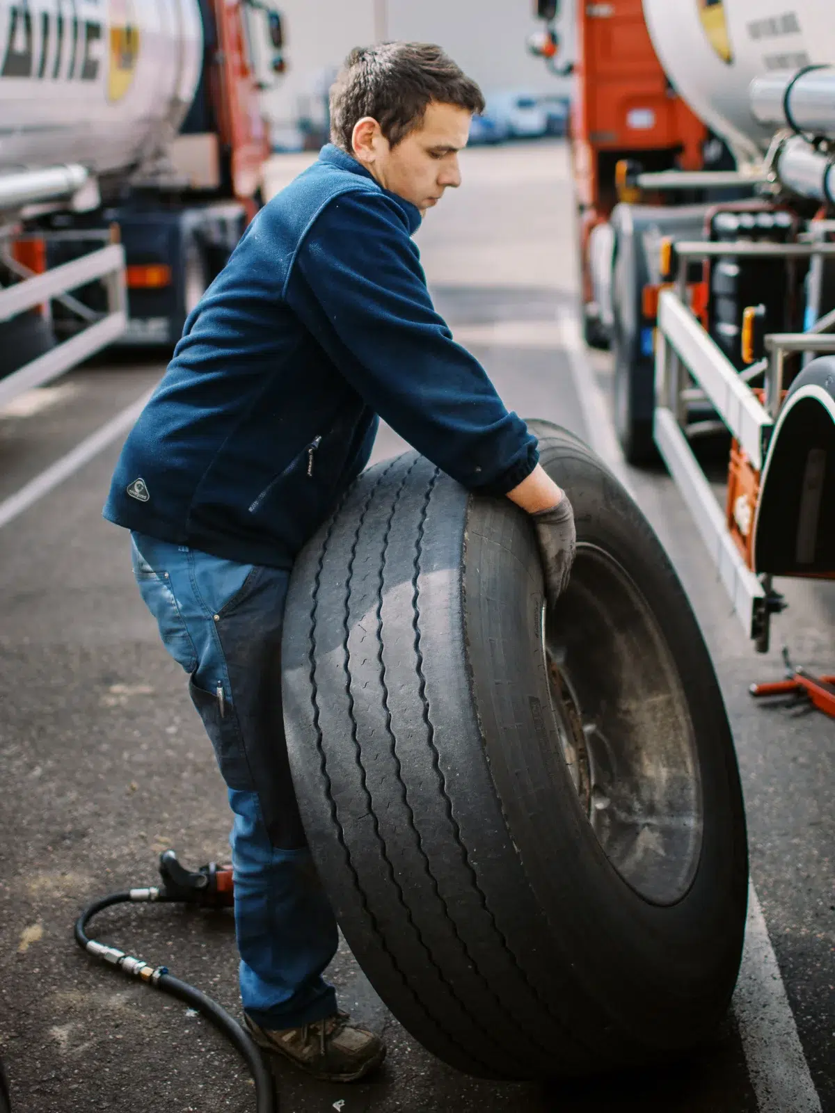Photographe reportage Lyon : Un mécanicien change le pneu d'un poids lourd dans un garage.