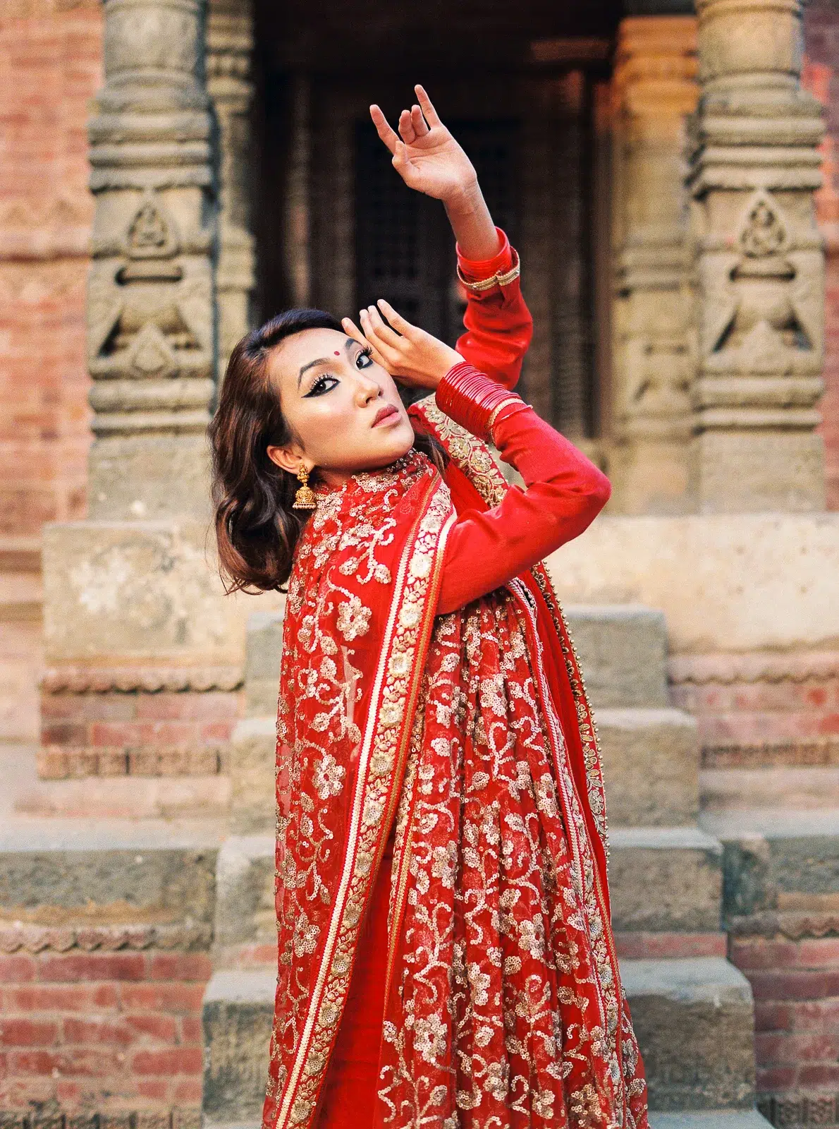 Photographe portrait Lyon : femme en sari rouge dansant devant un monument historique.