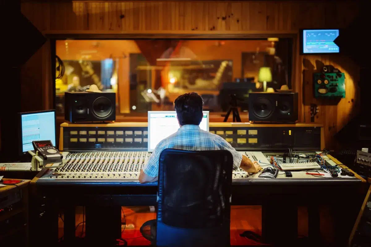Photo reportage Rhône Alpes : Ingénieur du son travaillant sur une console de mixage en studio.