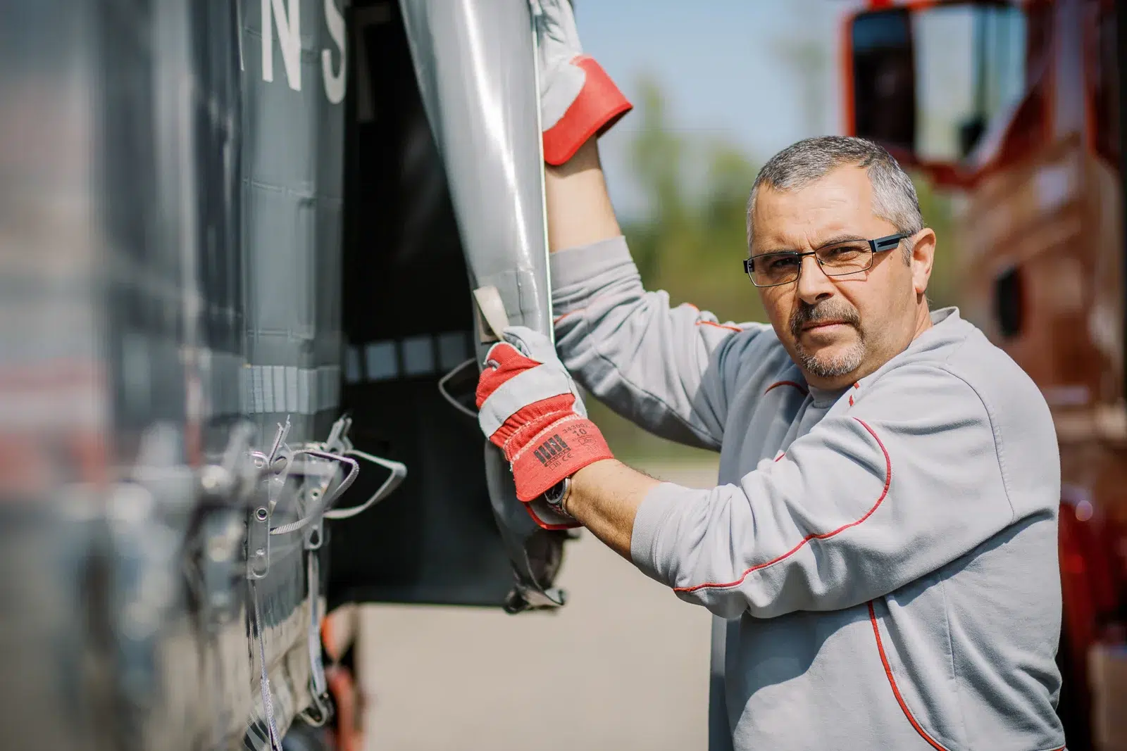 Photographe reportage Lyon : Un chauffeur routier ouvre la bâche de sa remorque.
