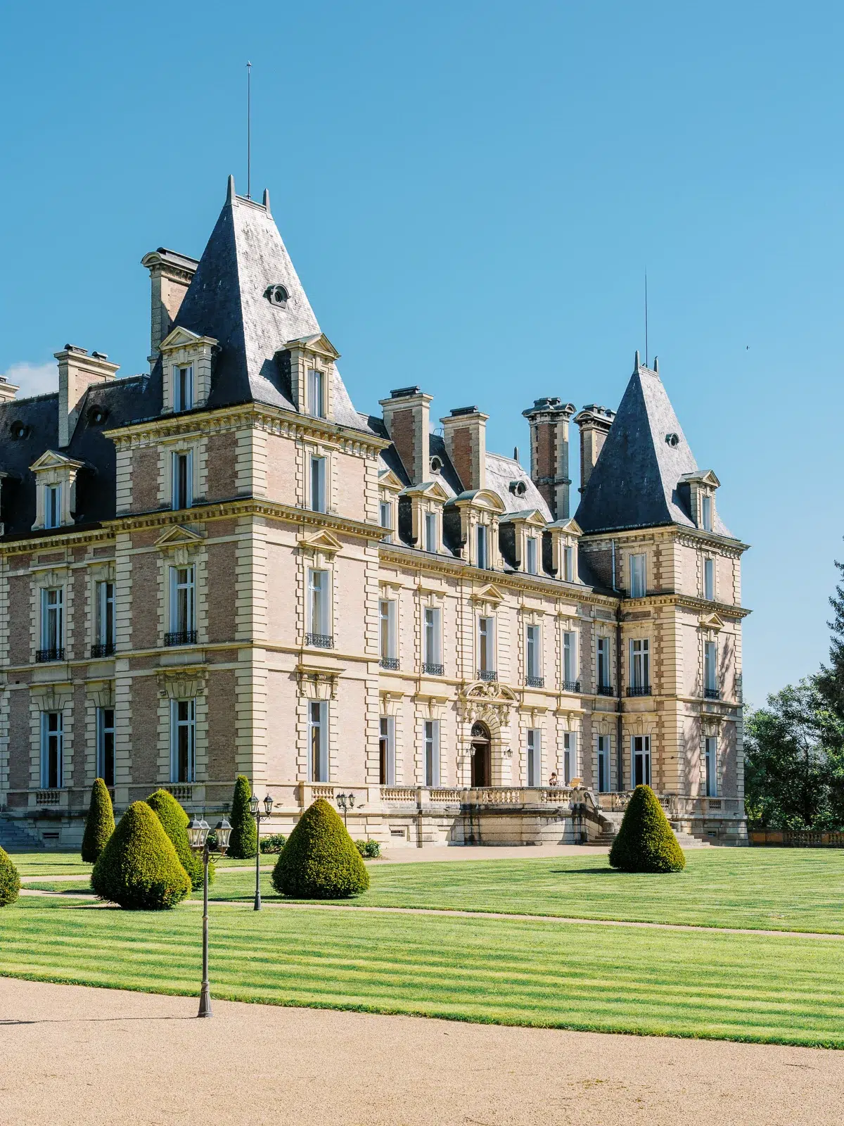 Photographe archi Lyon d'une propriété historique avec toitures en ardoise et pelouse.