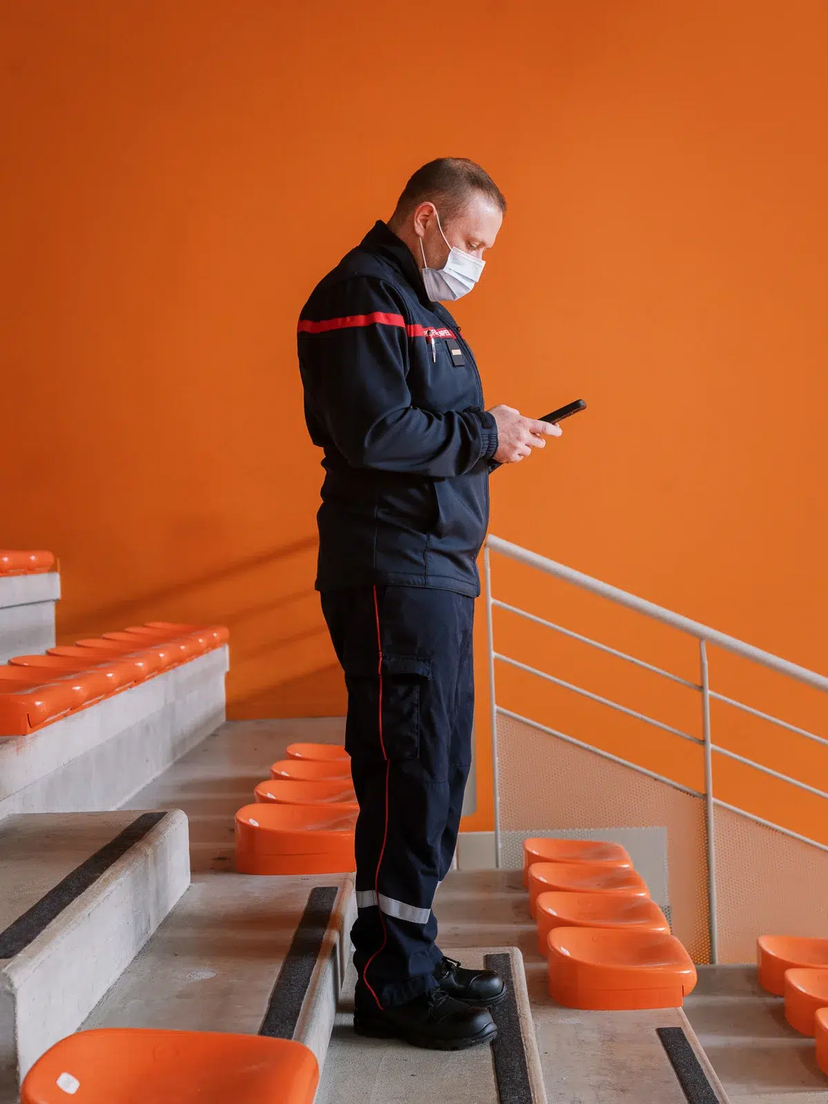 Reportage photo Lyon : Un pompier en uniforme consulte son téléphone dans des gradins.