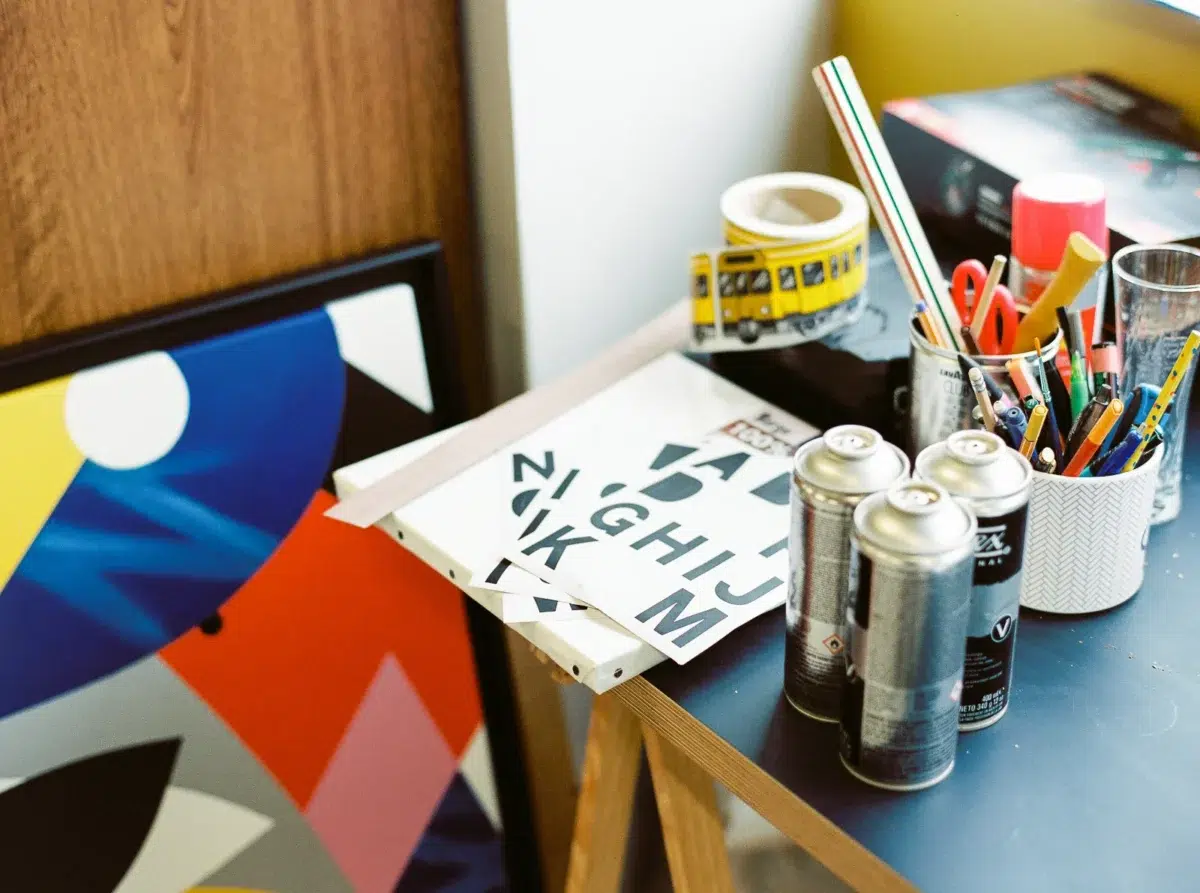 Photographe portrait Lyon : bombes de peinture et pinceaux sur le bureau d'un artiste.