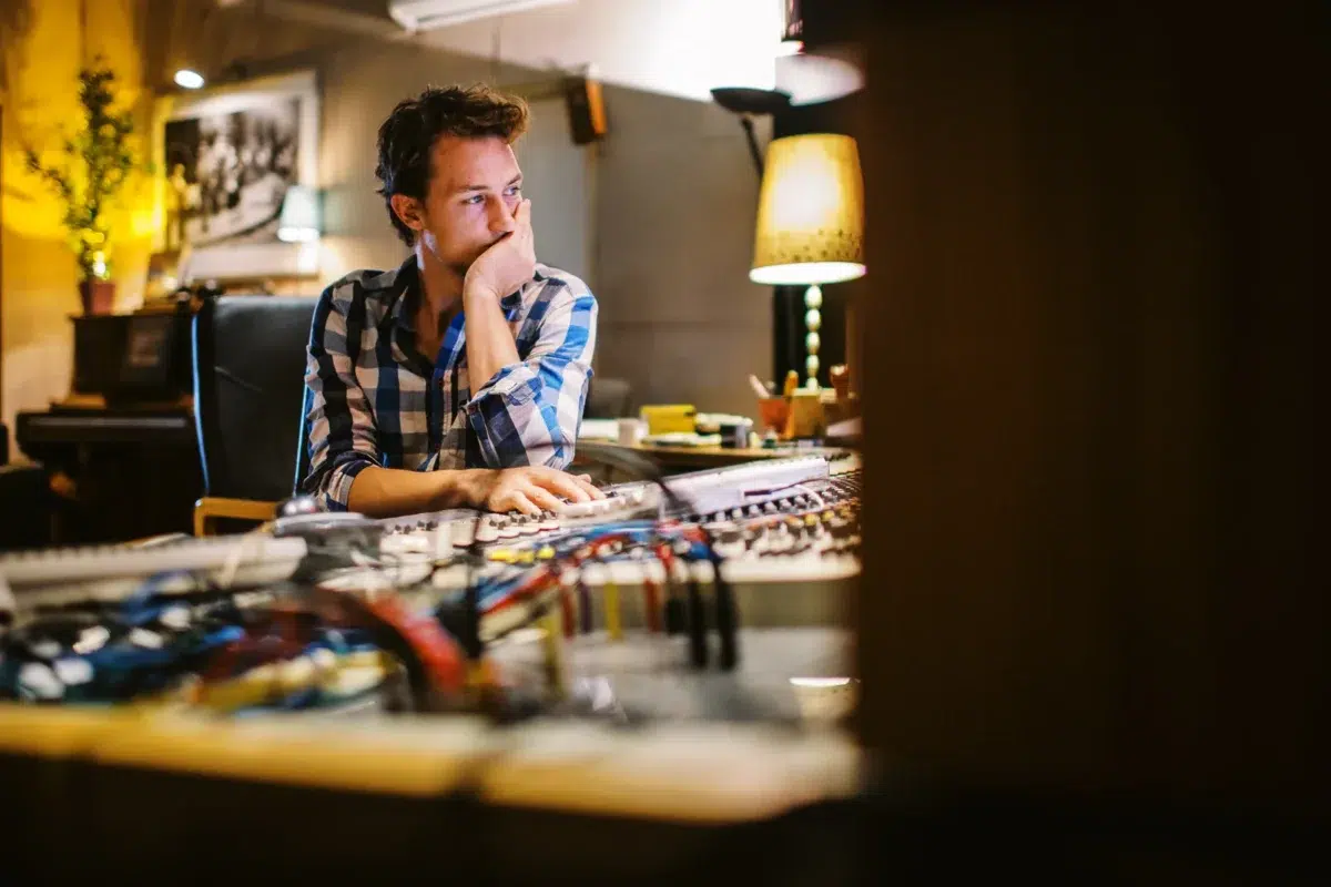Photo reportage Rhône Alpes : Ingénieur du son pensif devant sa console de mixage en studio.