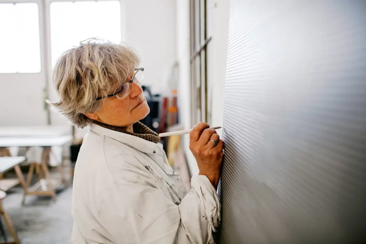 Reportage photo Lyon : Une artiste dessine sur une grande toile dans son atelier.