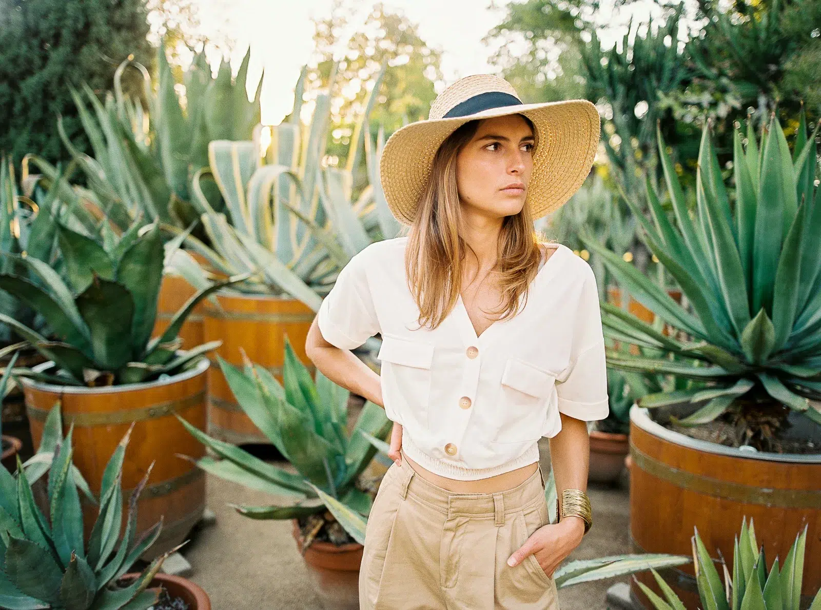 Photographe portrait Lyon : femme en tenue beige parmi de grandes plantes agaves.