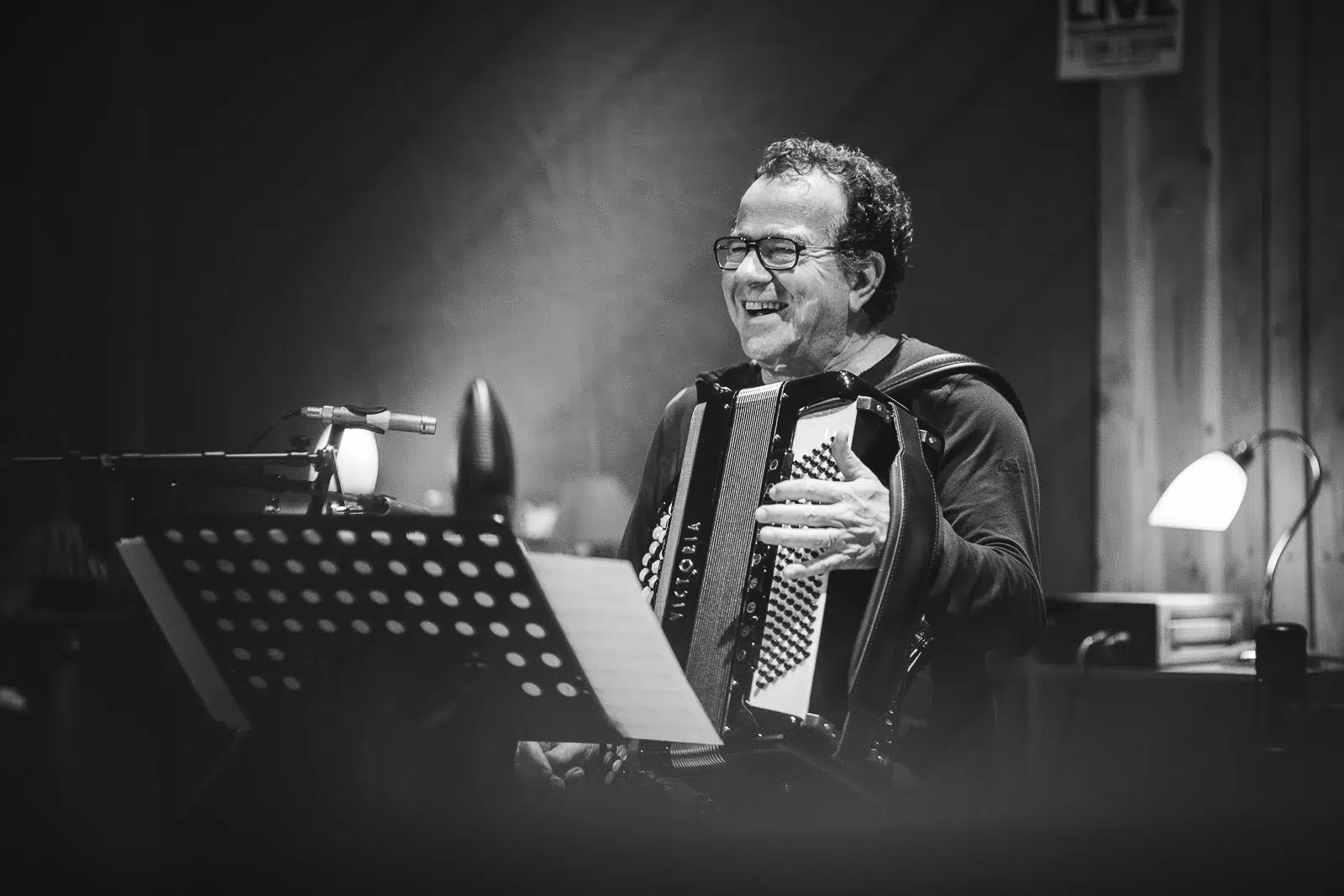 Photographe portrait Lyon : accordéoniste riant pendant une répétition en noir et blanc.
