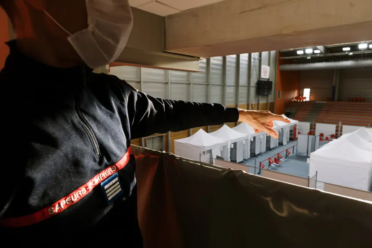 Photo reportage Rhône Alpes : Un pompier observe un centre de vaccination installé dans un gymnase.