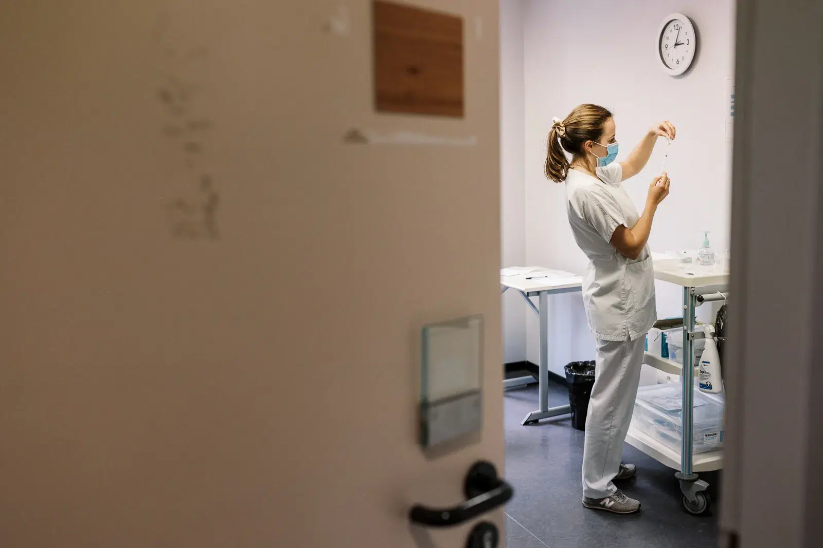 Photographe reportage Lyon : Une infirmière prépare une seringue dans une salle de soins.
