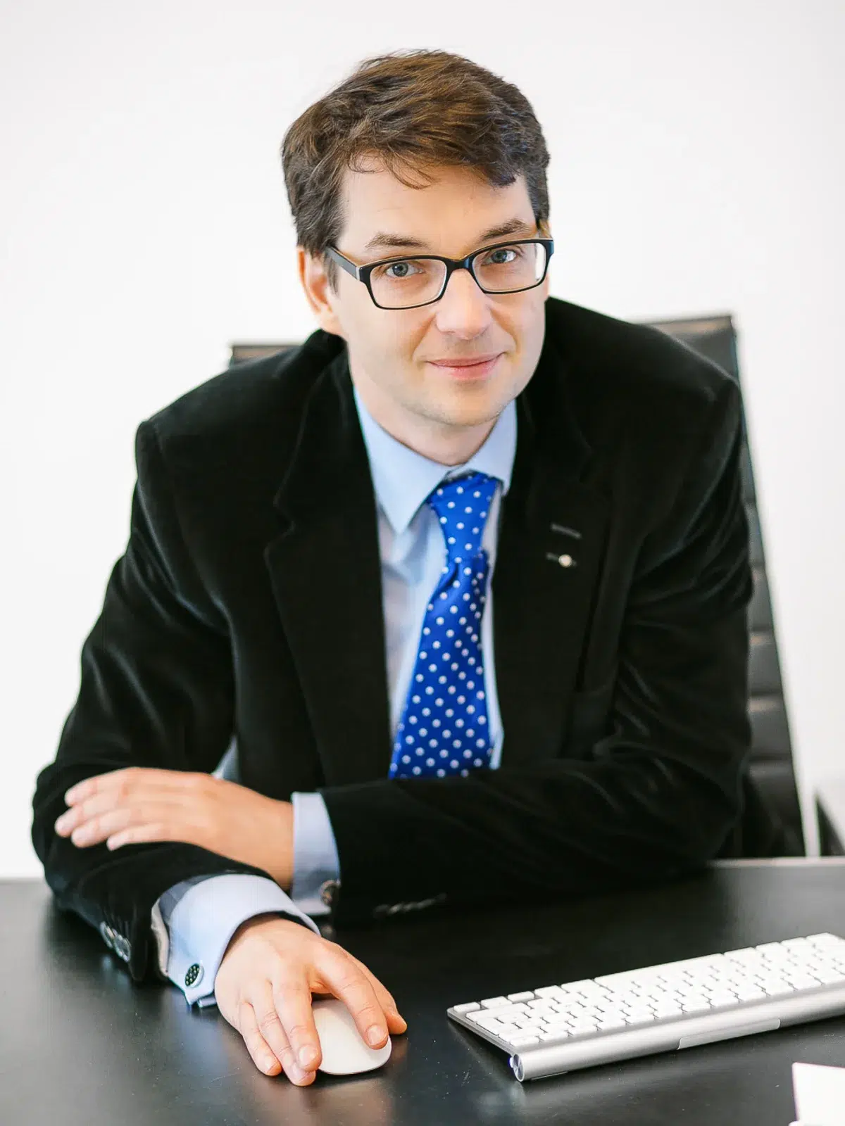 Photographe portrait Lyon : homme à lunettes assis à son bureau avec clavier et souris.