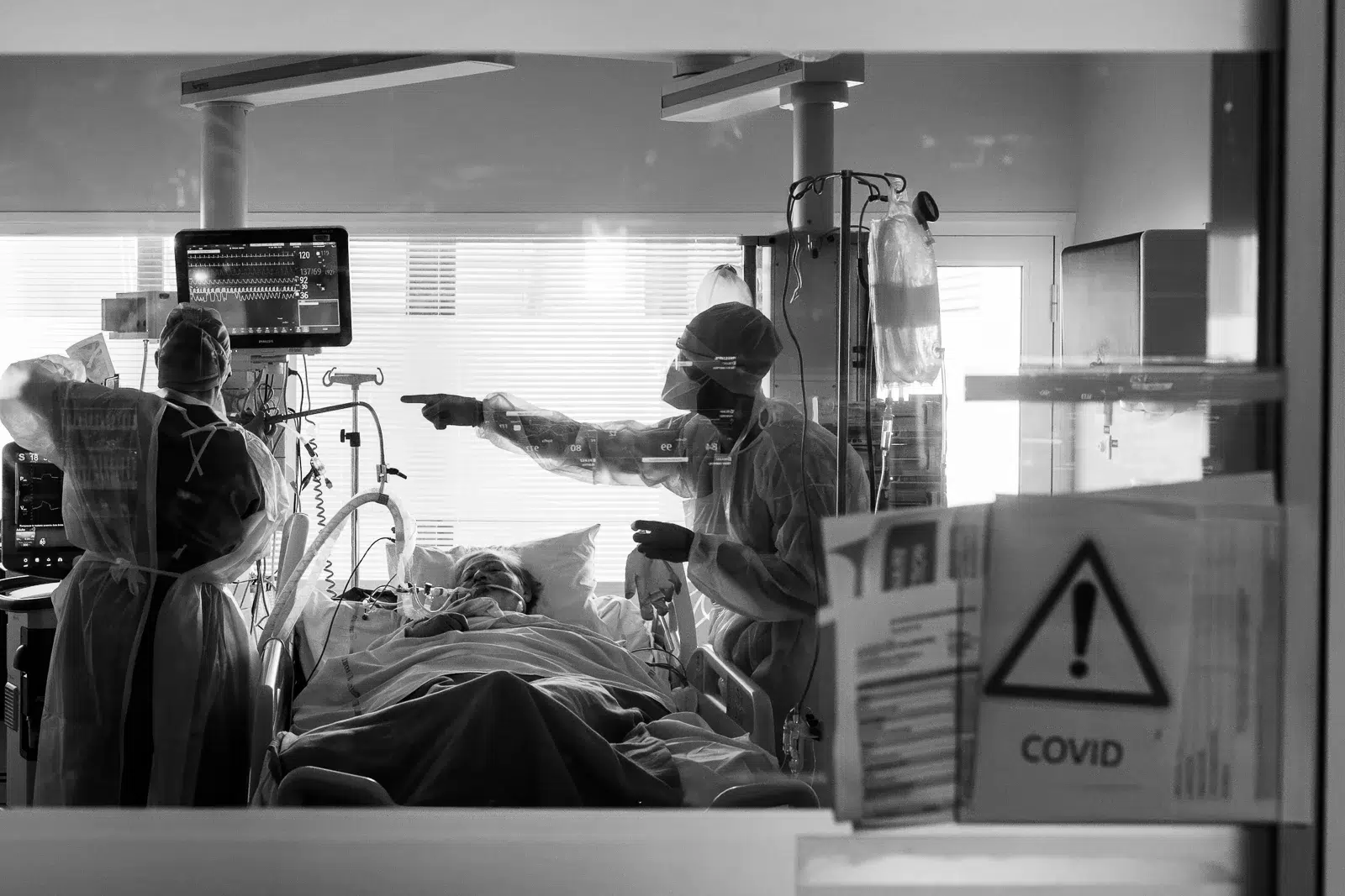 Photographe reportage Lyon : Deux soignants en tenue de protection s'occupent d'un patient en réanimation au HNO.