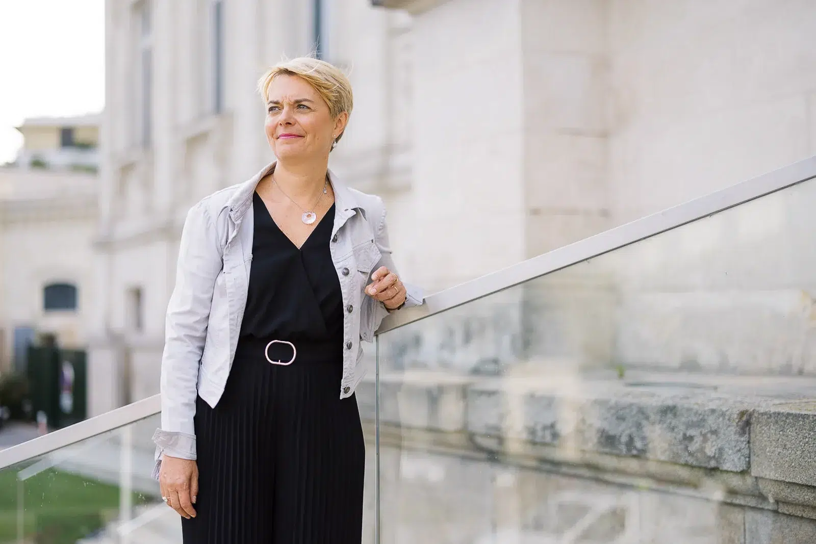 Photographe portrait Lyon : femme blonde en veste blanche posant sur un escalier en pierre.