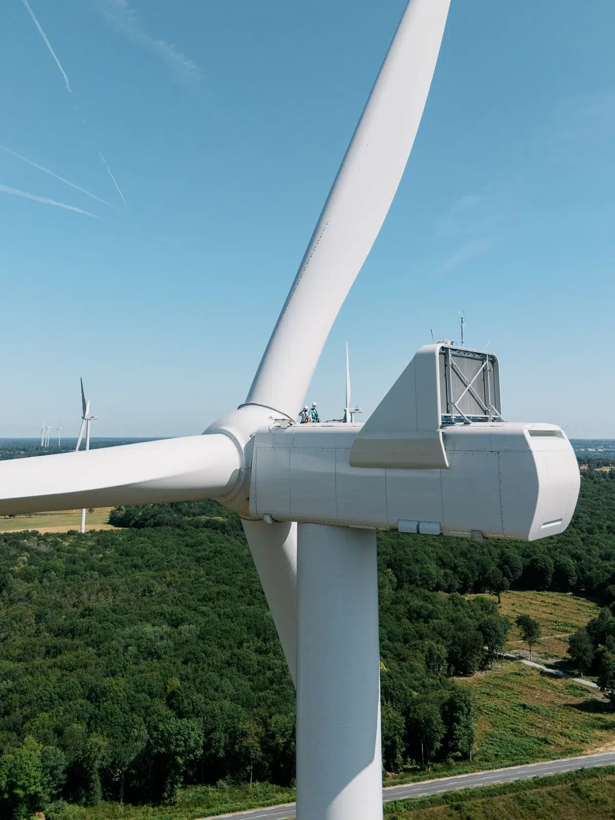 Reportage photo Lyon : Vue rapprochée de la nacelle d'une éolienne avec deux techniciens.