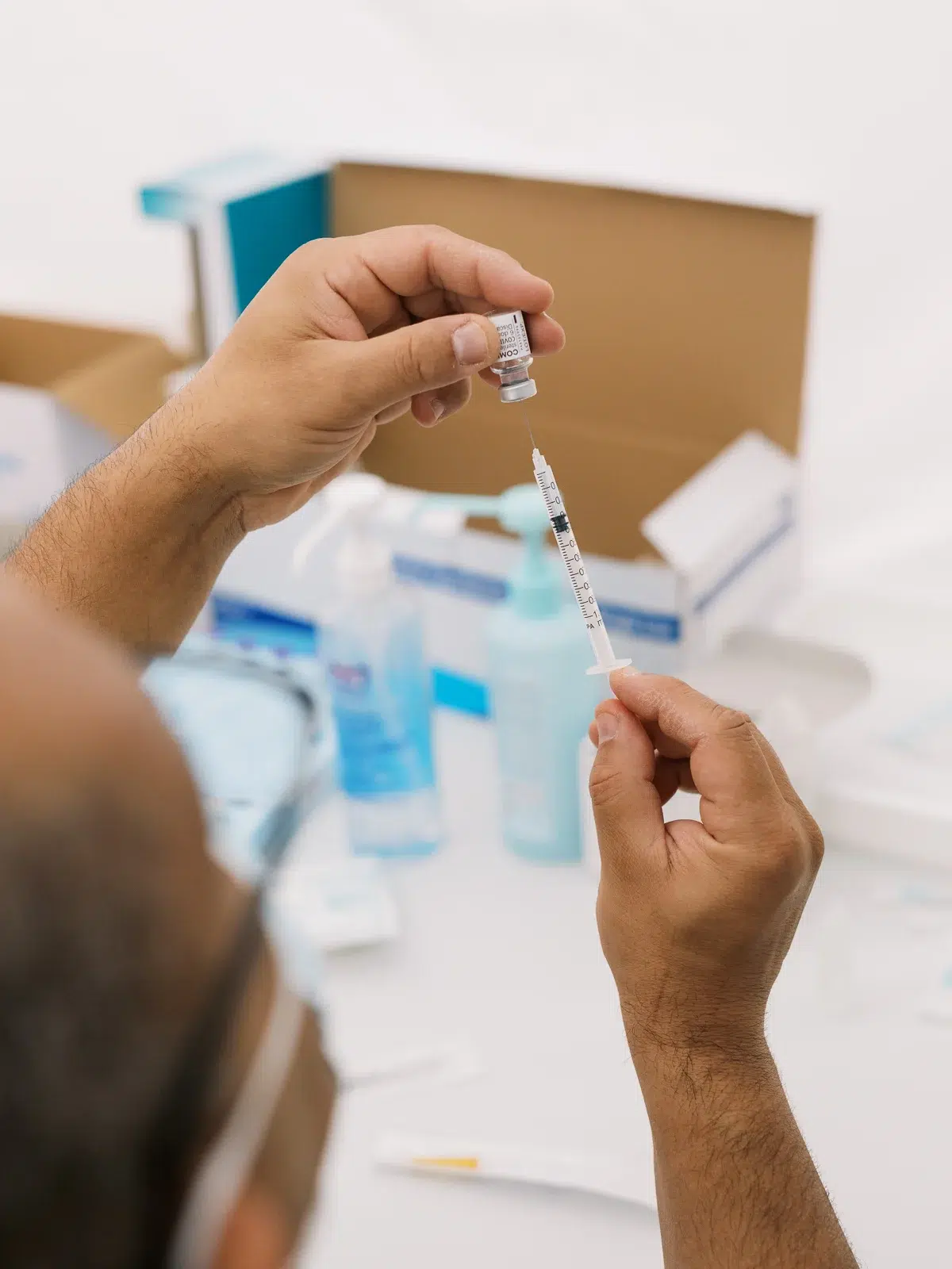 Photographe reportage Lyon : professionnel de santé préparant une seringue avec un flacon de vaccin dans un centre médical.