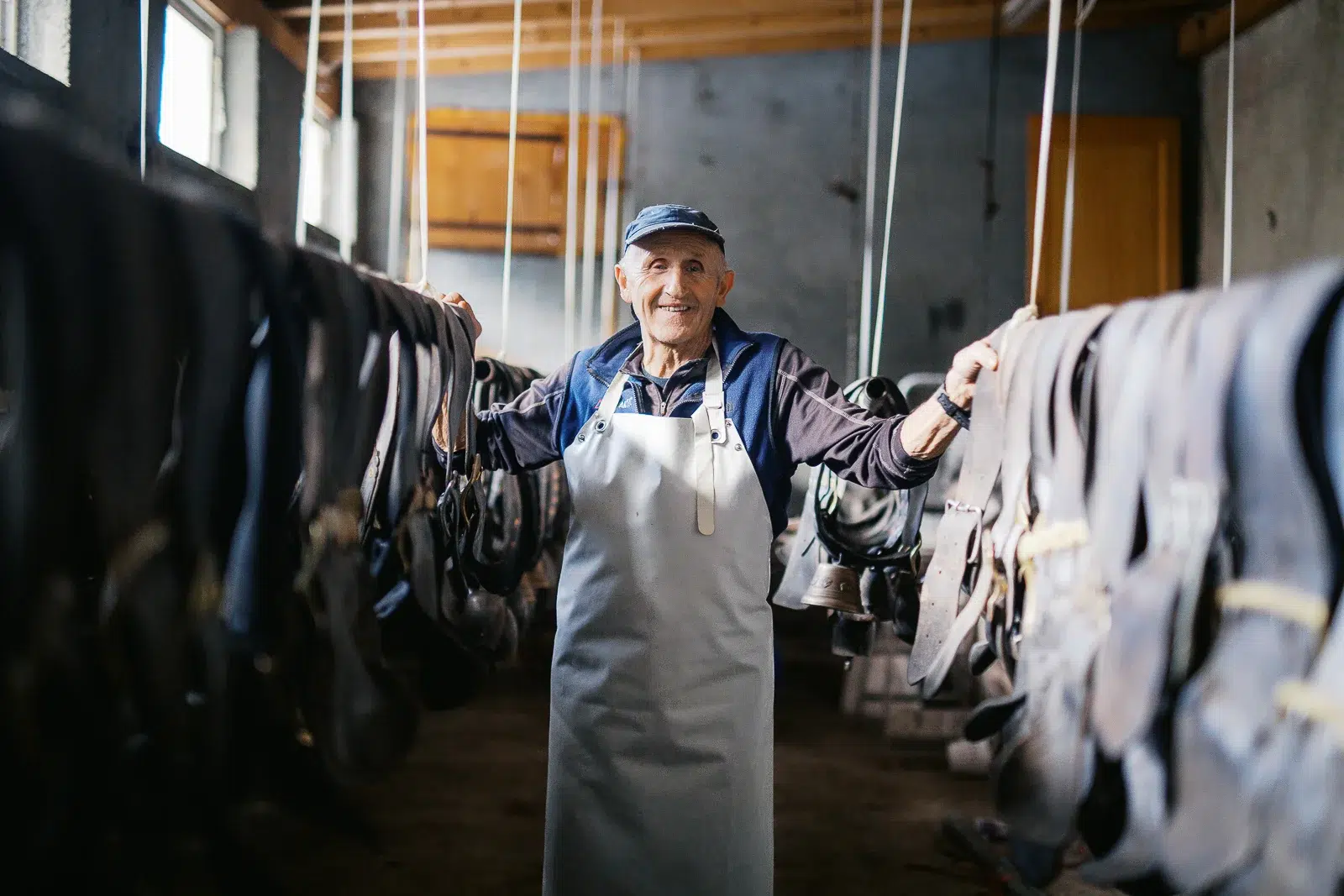 Photographe reportage Lyon : Portrait d'un artisan fromager souriant dans sa cave d'affinage.