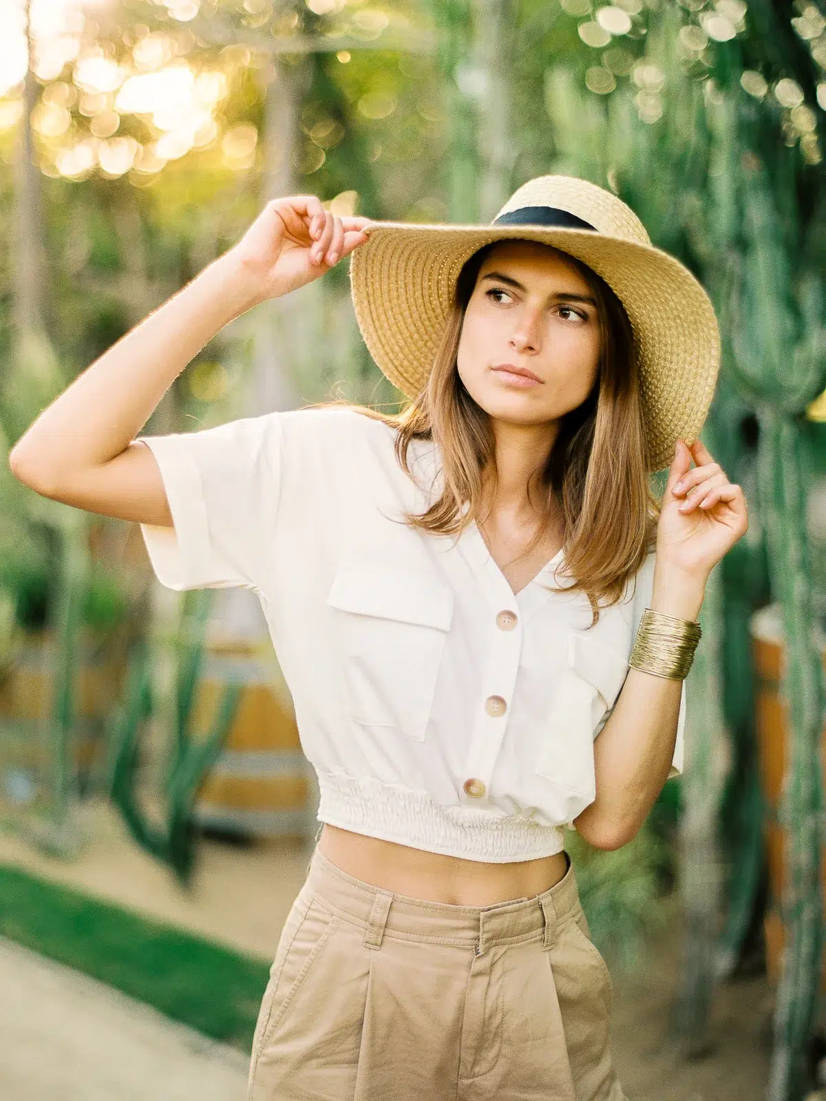 Photographe portrait Lyon : femme avec chapeau de paille dans un jardin de cactus au soleil.
