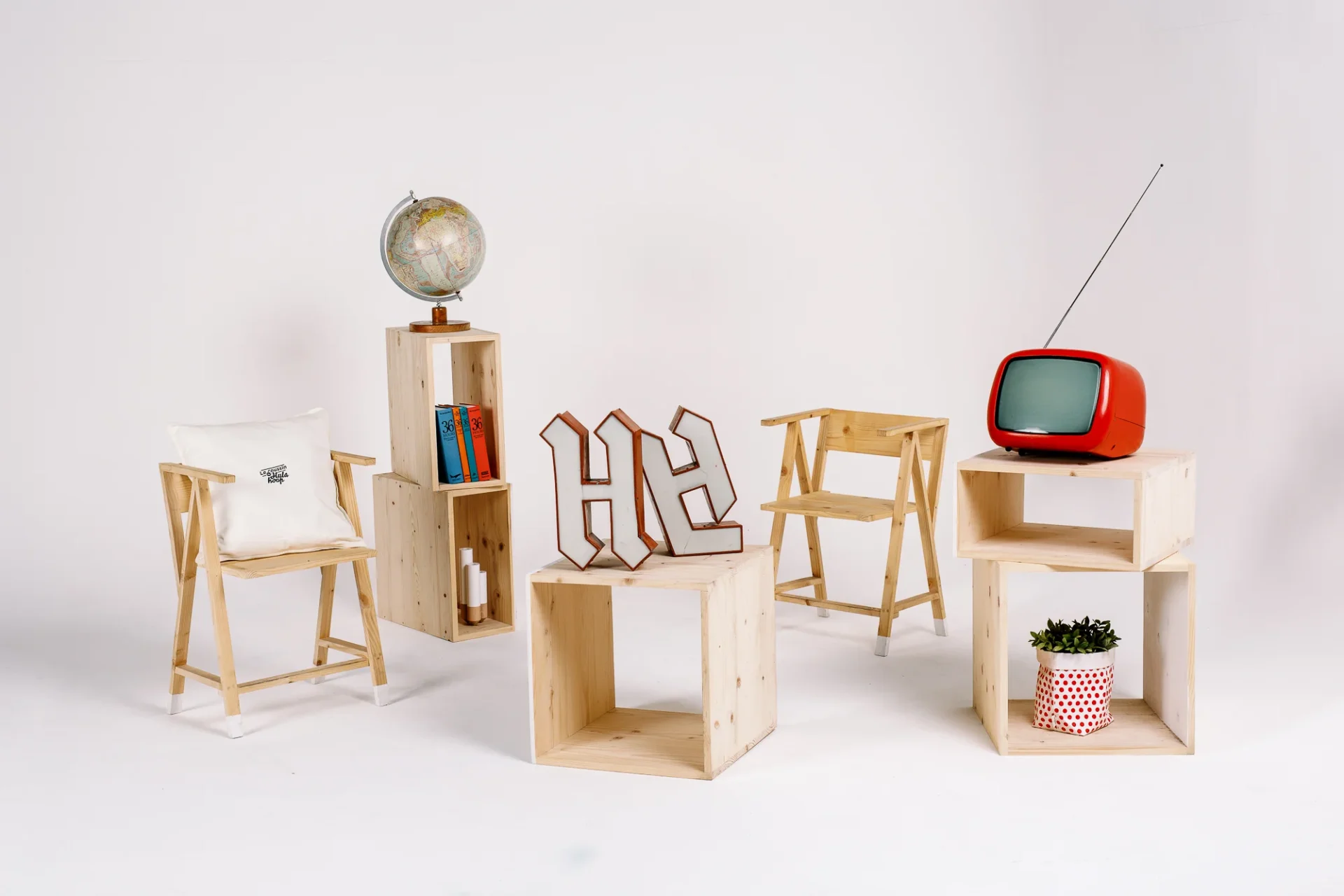 Agence de communication Hula Hoop : décor de studio avec caisses en bois, télévision rouge vintage et lettres HH.