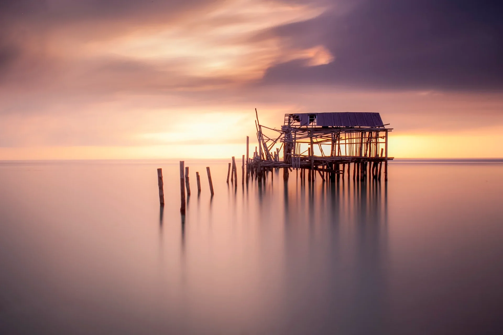 Cabane sur pilotis au coucher du soleil, exposition voyage en Asie.