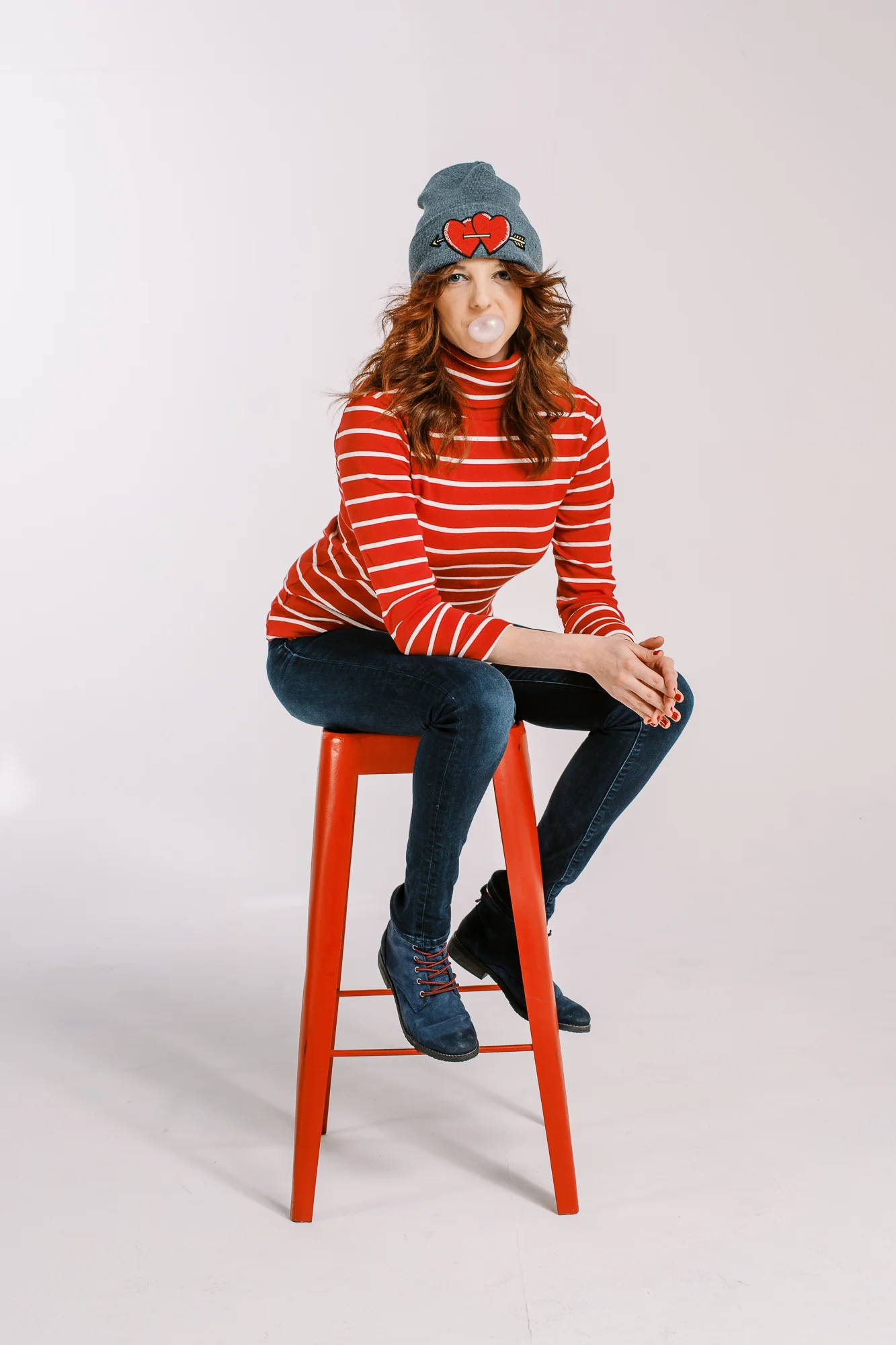 Agence de communication Hula Hoop : femme en marinière rouge faisant une bulle de chewing-gum sur un tabouret.