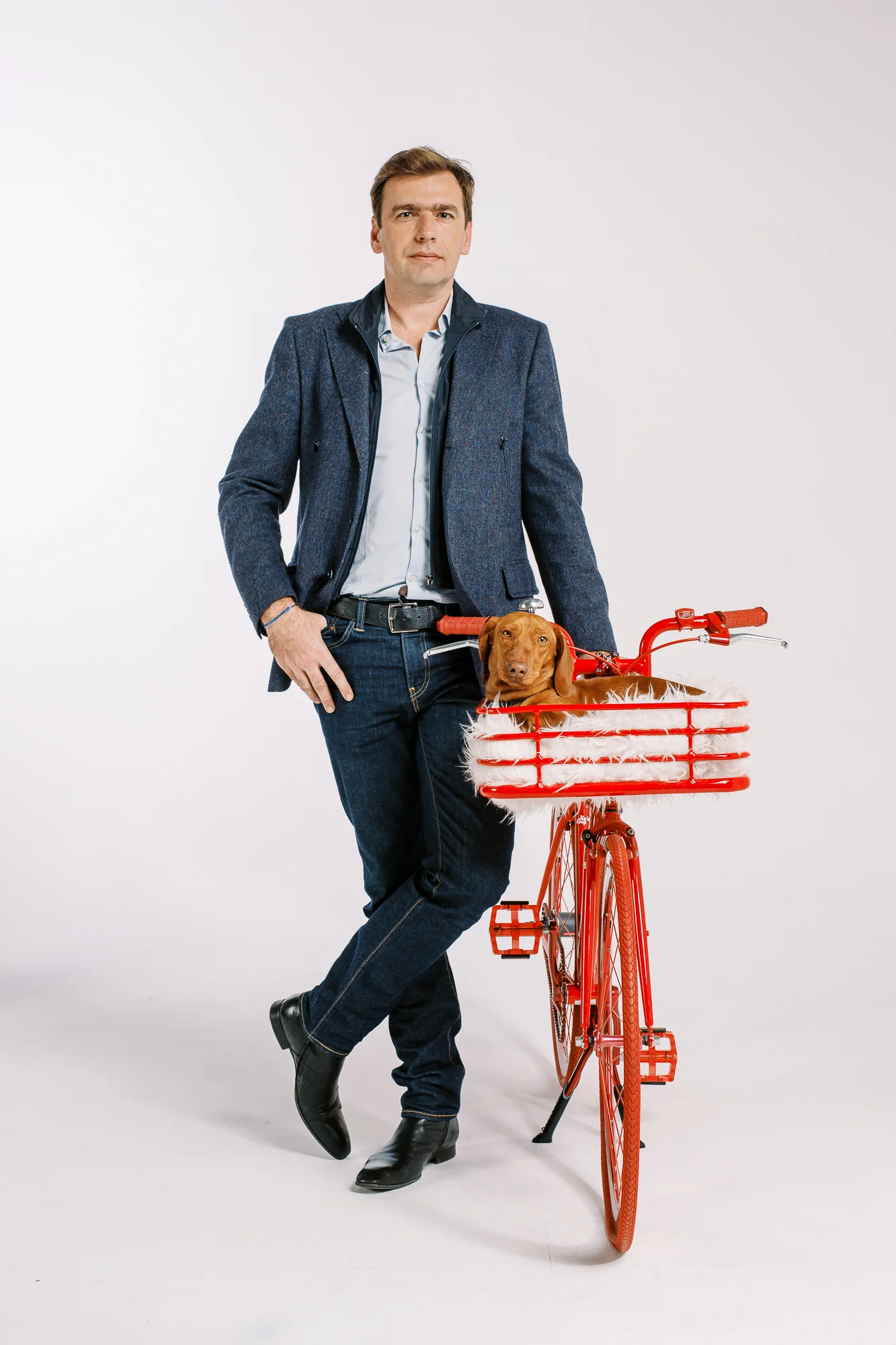 Photos portraits agence de com' : homme en veste bleue posant avec un teckel dans le panier d'un vélo rouge.