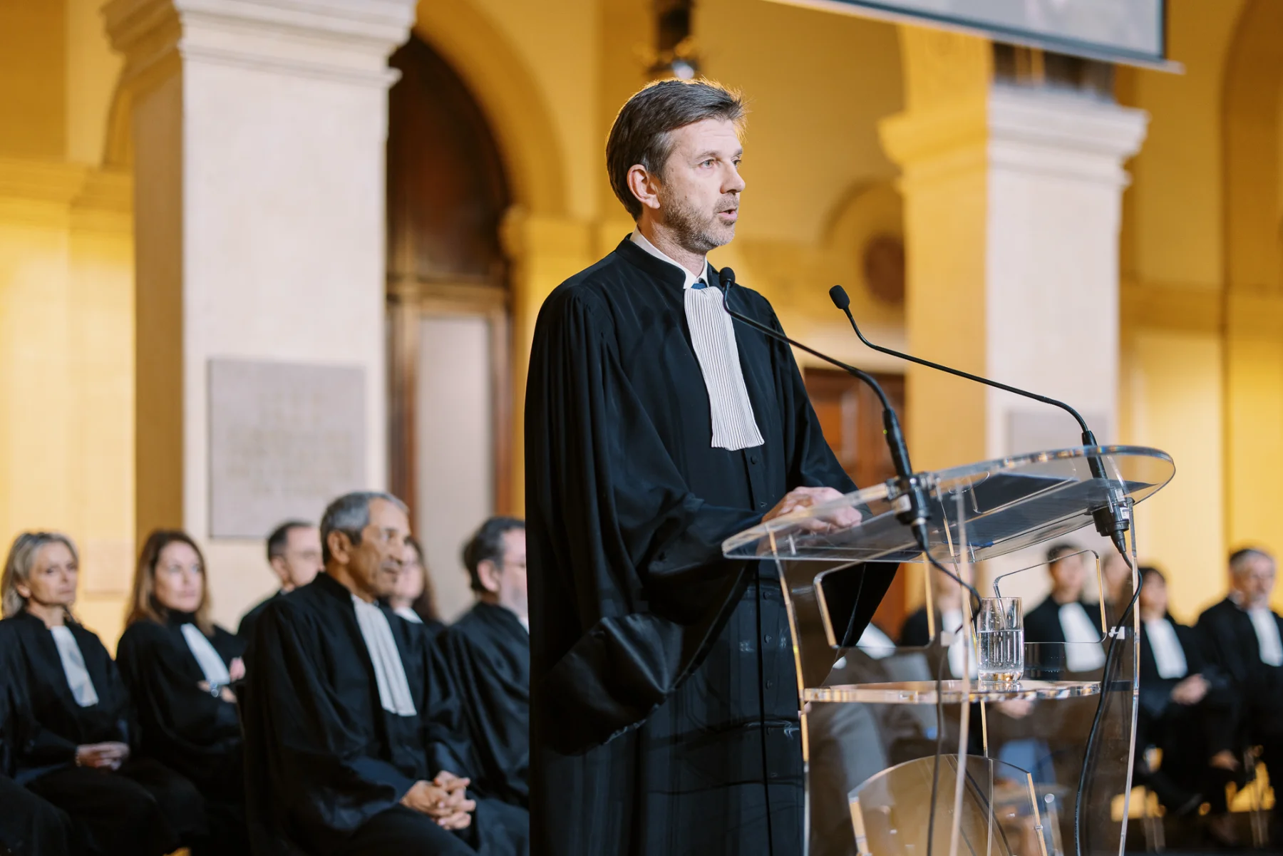 Avocat en robe s'exprimant au pupitre d'un tribunal, un exemple pour trouver photographe d'événementiel.