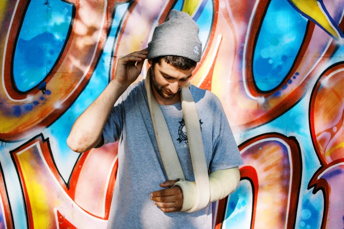 Homme au bras plâtré devant un graffiti par un photographe artiste Lyon.