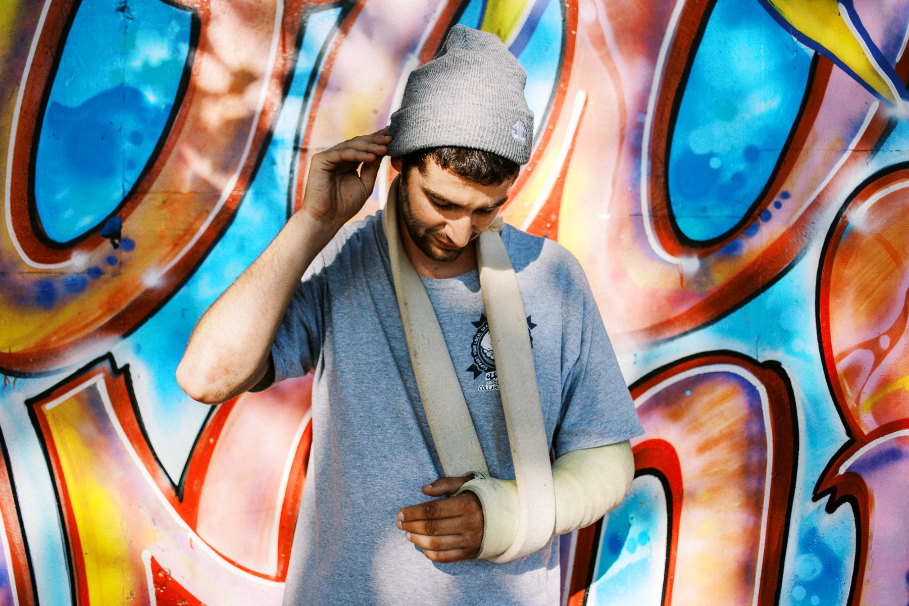 Homme au bras plâtré devant un graffiti par un photographe artiste Lyon.