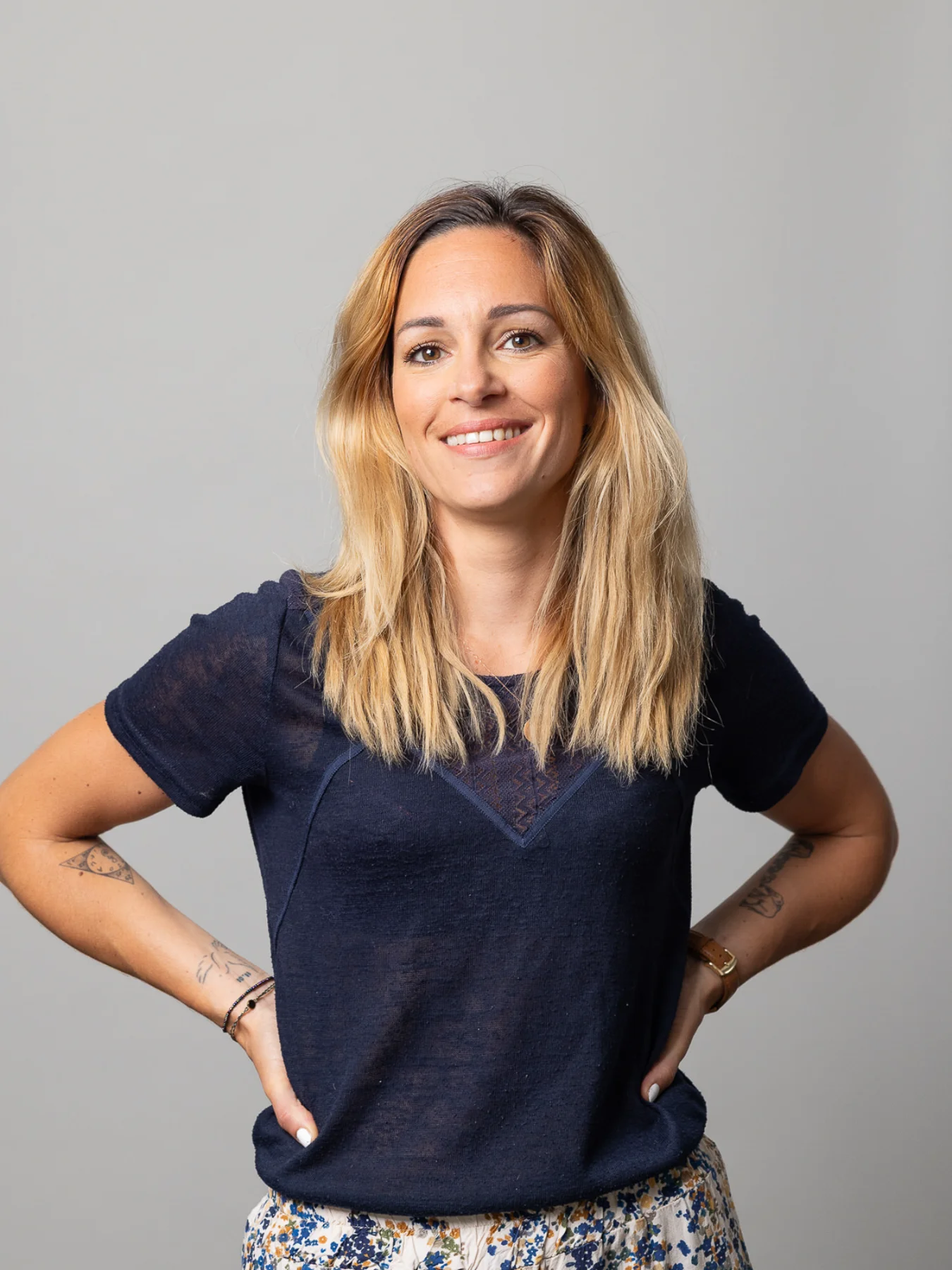 Femme blonde souriante posant les mains sur les hanches. Idéal pour trouver un bon photographe de studio.